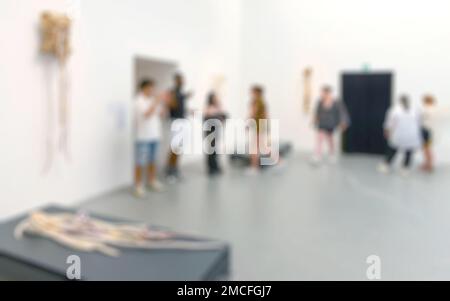 Zuschauer, die Gemälde und Skulpturen in der Kunstausstellungsgalerie betrachten. Unscharfer Hintergrund. Stockfoto