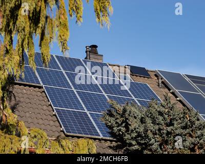 Solarzellenpaneele auf dem Dach eines einzigen Familienhauses. Erzeugung erneuerbarer Energie für ein Wohngebäude. Photovoltaik-Technologie auf einem Dach. Stockfoto