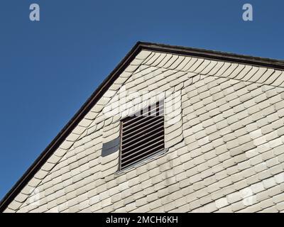 Asbestfassade eines Wohngebäudes in der DDR. Graue Faserzementplatten als Verkleidungen an einer Außenwand. Das Material ist gefährlich. Stockfoto