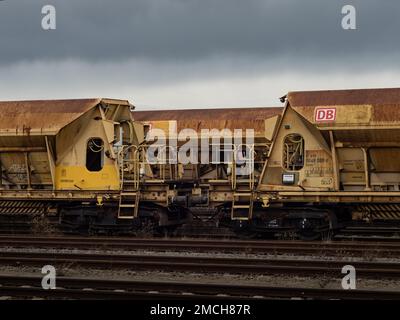 Facns 141 offene Güterwagen der Deutschen Bahn. Rostiger Stahl auf den Schienen in dunkler Umgebung. DB-Ladeballastierwagen als Technologie. Stockfoto