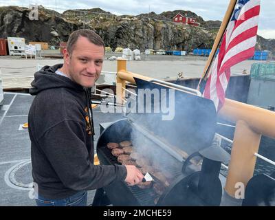 Petty Officer 1. Class Nicholas Loeven grillt Burger auf der Flucht der USA Küstenwache Cutter Oak, 3. Juli 2022. Loeven und sein kulinarisches Expertenteam haben eine Mahlzeit für die Besatzung im Juli 4. zusammengestellt, während sie einen Hafen in Sisimiut, Grönland, anlegt. USA Foto der Küstenwache von Petty Officer 2. Klasse Diana Sherbs. Stockfoto