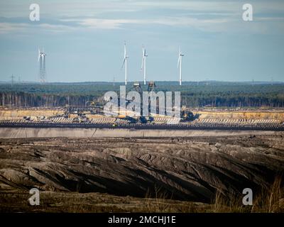 Kohlebagger in einem Tagebau in Nochten. Tief in der Erde graben und die Natur zerstören. Windturbinen sind als Kontrast im Hintergrund Stockfoto