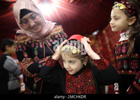 Gaza, Palästina. 19. Januar 2023. Suhaila Shaheen, 60, streichelt ihre Enkelkinder in ihrem eigenen Museum in Rafah, südlich des Gazastreifens. Eine palästinensische Frau Suhaila Shaheen, 60, gründete ein Museum zum Kulturerbe, das die Sammlungen, die sie gesammelt hat, und das, was sie auf ihre Kosten gekauft hat, enthält. Um das Ziel zu erreichen, das erste Museum mit dem Namen seiner Stadt, Rafah, zu errichten. Kredit: SOPA Images Limited/Alamy Live News Stockfoto