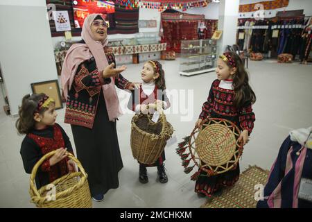 Gaza, Palästina. 19. Januar 2023. Suhaila Shaheen, 60, streichelt ihre Enkelkinder in ihrem eigenen Museum in Rafah, südlich des Gazastreifens. Eine palästinensische Frau Suhaila Shaheen, 60, gründete ein Museum zum Kulturerbe, das die Sammlungen, die sie gesammelt hat, und das, was sie auf ihre Kosten gekauft hat, enthält. Um das Ziel zu erreichen, das erste Museum mit dem Namen seiner Stadt, Rafah, zu errichten. Kredit: SOPA Images Limited/Alamy Live News Stockfoto