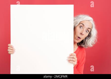 Überraschend reife Frau mit leerem Brett Stockfoto