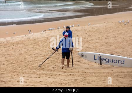 Australisches Paar, das einen Metalldetektor am Manly Beach im Sommer 2023 benutzt, auf der Suche nach Metallgegenständen und vergrabenen Schatzmünzen, Sydney, NSW, Australien Stockfoto