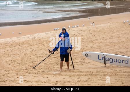 Australisches Paar, das einen Metalldetektor am Manly Beach im Sommer 2023 benutzt, auf der Suche nach Metallgegenständen und vergrabenen Schatzmünzen, Sydney, NSW, Australien Stockfoto