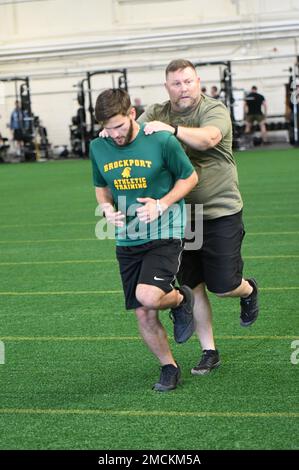 Mike Tribble, ein zertifizierter Spezialist für Pose-Methoden im ganzheitlichen Gesundheits- und Fitness-Programm der Combat Aviation Brigade (H2F) aus dem Jahr 10., demonstriert einen Widerstandsbohrer, indem er ihn auf die Schultern eines Läufers setzt. Tribble leitet einen fünfwöchigen Kurs zur Pose-Methode für Soldaten in der 10. Mountain Division, der ihnen hilft, schneller, effizienter und mit geringerem Verletzungsrisiko zu laufen. (Foto von Mike Strasser, Fort Drum Garrison Public Affairs) Stockfoto