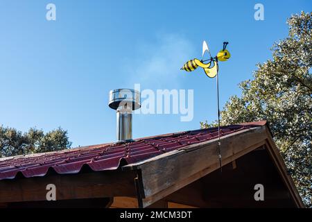 Eine Wespenform, die sich mit dem Wind auf dem Dach eines Holzhauses bewegt. Stockfoto