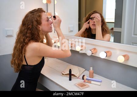 Junge Ballerina, die vor dem Spiegel Mascara aufträgt. Stockfoto