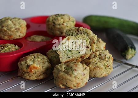 Frühstücksmuffins mit Käse und Zucchini. Herzhafte Frühstücksmuffins aus Vollkornmehl, zerkleinerten Zucchini, geriebenem Käse und Kräutern. Aufnahme auf weißem Hintergrund Stockfoto