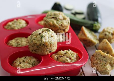 Frühstücksmuffins mit Käse und Zucchini. Herzhafte Frühstücksmuffins aus Vollkornmehl, zerkleinerten Zucchini, geriebenem Käse und Kräutern. Aufnahme auf weißem Hintergrund Stockfoto