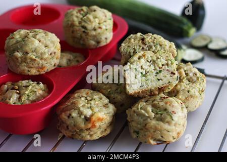 Frühstücksmuffins mit Käse und Zucchini. Herzhafte Frühstücksmuffins aus Vollkornmehl, zerkleinerten Zucchini, geriebenem Käse und Kräutern. Aufnahme auf weißem Hintergrund Stockfoto