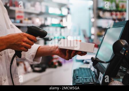 Der Apotheker verwendet einen Strichcodeleser, um ein Medikament zu identifizieren und zu verkaufen Stockfoto