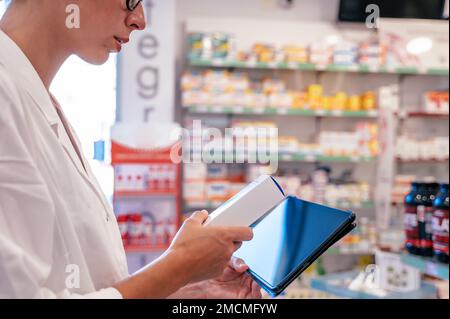 Eine Apothekerin prüft die Arzneimittel auf der Tablette Stockfoto