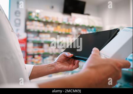 Eine Apothekerin prüft Informationen zu Arzneimitteln auf der Tablette Stockfoto