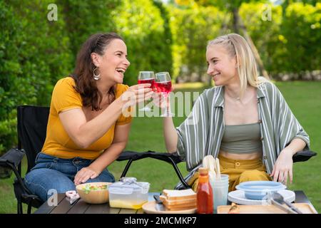 Glückliche Familie mit Barbecue, bbq, Party mit Rotwein im Garten des Hauses im Freien mit Happy Meal am Sommerferienwochenende Stockfoto