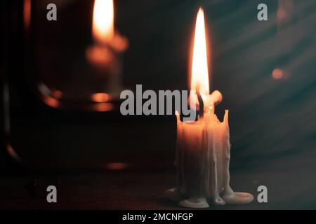 Eine brennende Kerze wurde von Spiegeln getragen und Wahrsagerkarten liegen in der Nähe, Wahrsagerei auf Karten bei Kerzenlicht auf einem schwarzen Tisch, Magie, Hexe A Stockfoto