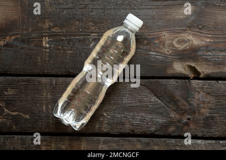 Plastikflasche mit Wasser liegt auf einem alten Holztisch, Flasche mit Wasser, Wasser Stockfoto