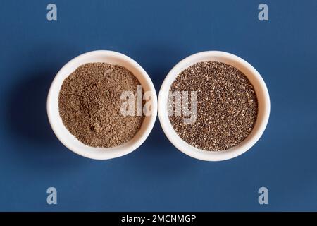 Draufsicht einer Nahaufnahme zweier Keramikschüsseln nebeneinander mit ganzer und pulverisierter Chia. Gesundes Saatgut zu essen. Stockfoto