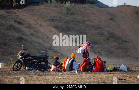 Pushkar, Rajasthan, Indien - November 2022: Gruppe von Familienmitgliedern, die während des Kamelmärchens in der Wüste von pushkar sitzen. Stockfoto