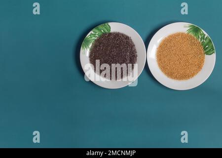 Ein Blick von oben auf zwei weiße Teller, dekoriert mit bemalten Blättern, gefüllt mit weichen Flachs- und Chiasamen, auf einem türkisfarbenen Studio-Hintergrund mit Kopierbereich. Stockfoto