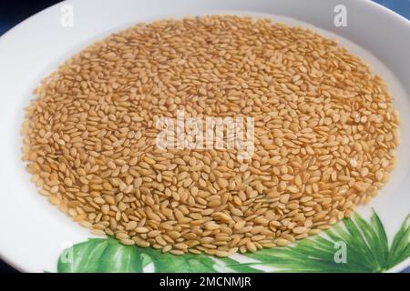 Getränkte rohe Leinsamen auf einem weißen Gericht mit gemalten grünen Blattmotiven. Superfood und Gesundheit. Stockfoto
