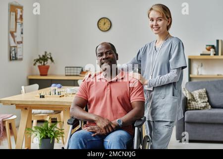 Porträt eines jungen Freiwilligen mit einem älteren Mann, der im Raum steht und vor der Kamera lächelt Stockfoto