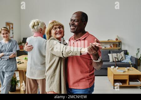 Glückliches Seniorenpaar, das während des Unterrichts im Pflegeheim tanzen lernt Stockfoto