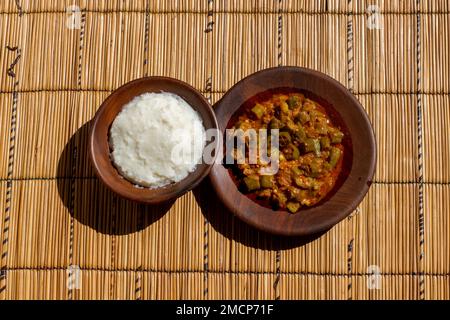 Okra- und Tomateneintopf, eine klassische Kombination, mit dem Zusatz von Ugali, einem Grundgericht aus Maismehl, ist eine sättigende und leckere Mahlzeit Stockfoto