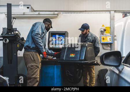 Ingenieure, die in einer modernen Autoreparaturwerkstatt mit modernster Ausrüstung arbeiten. Hochwertige Fotos Stockfoto