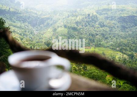 Eine Tasse Ceylon-Tee mit Blick auf grüne Hügel und Teeplantagen in Sri Lanka, Asien Stockfoto