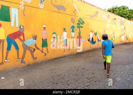 Einheimische Männer schauen auf das Wandgemälde, die Graffiti-Mauer, auf einem Gebäude im Stadtviertel Achada Grande Frente in Praia, Insel Santiago, Cabo verde Stockfoto