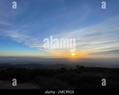 Ein malerischer Blick auf einen hellen Sonnenuntergang am Himmel über dem Horizont, vom Berggipfel aus gesehen Stockfoto