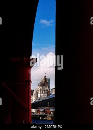 Das Liver Building, das durch die imposanten rot bemalten Säulen des renovierten Royal Albert Dock in Liverpool gesehen wird Stockfoto