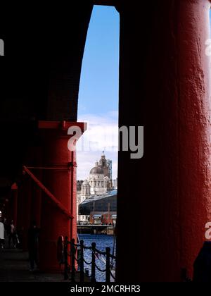 Das Liver Building, das durch die imposanten rot bemalten Säulen des renovierten Royal Albert Dock in Liverpool gesehen wird Stockfoto