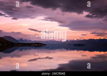 Sonnenaufgang über einem spiegelruhigen Lake Tekapo und schneebedeckten Bergen in Neuseeland Stockfoto