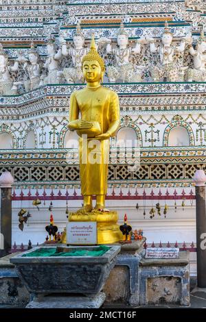 Bangkok, Thailand - März 19. 2018: Eine goldene Statue am Fuße des zentralen Prang (Turm) im buddhistischen Tempel Wat Arun (Tempel der Morgenröte). Stockfoto