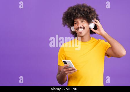 Ein glücklicher afrikaner, der mit Kopfhörern und einem Handy Musik hört Stockfoto