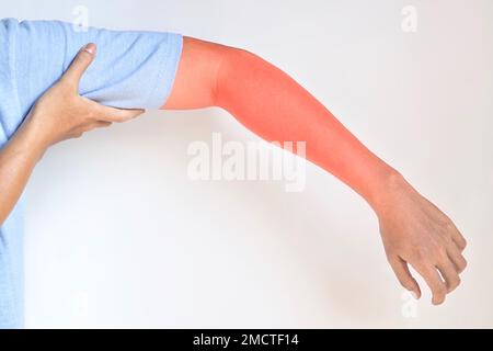 Schmerzen im Oberarm südostasiatischer junger Mann. Konzept von Ellenbogen- und Unterarmschmerzen, Verletzungen oder Muskelproblemen. Stockfoto