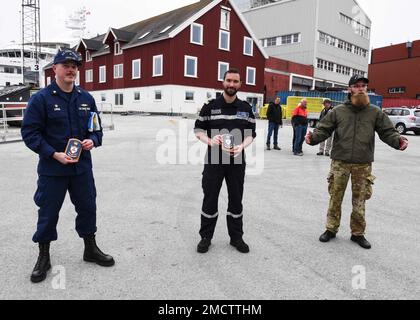 UCGC Oak (WLB 211) Befehlshaber LT. Commander. Jacob Loman und der befehlshabende Offizier des französischen Marineschiffs Fulmar nehmen bei einer Begegnung in Nuuk, Grönland, am 9. Juli 2022 Tafeln des befehlshabenden Offiziers des dänischen Marineschiffs Ejnar Mikkelsen an. USA Mitglieder der Küstenwache und aus Frankreich, Dänemark und Grönland trafen sich zu einem moralischen Ereignis am Ende der fünftägigen Übung Argus. USA Foto der Küstenwache von Petty Officer 2. Klasse Diana Sherbs. Stockfoto