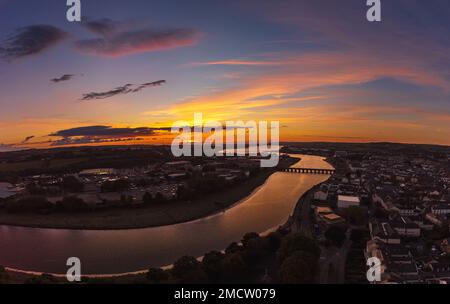Ein Blick aus der Vogelperspektive auf einen Fluss, der während des Sonnenuntergangs durch die Stadt fließt Stockfoto