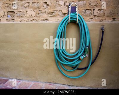 Ein Gartenschlauch, der an einer lehmwand in einem Landhaus in der Nähe der Kolonialstadt Villa de Leyva im Zentrum Kolumbiens hängt. Stockfoto