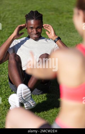 Weibliche Personal-Trainerin hält die Füße eines männlichen Athleten Stockfoto