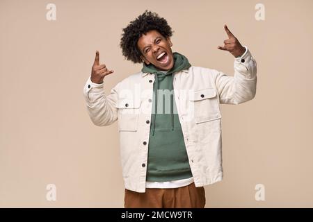 Ein cooler afroamerikanischer Teenager, der ein Rock 'n' Roll-Handzeichen zeigt, isoliert auf Beige. Stockfoto