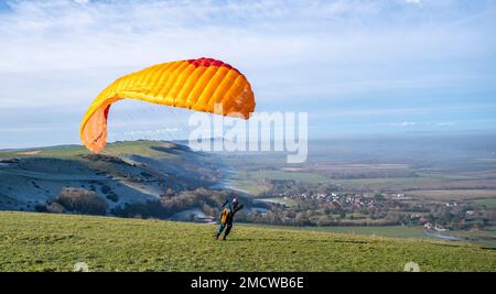 Brighton UK 22. Januar 2023 - Ein Gleitschirm fliegt in den Nebel von Devils Dyke entlang des South Downs Way in der Nähe von Brighton an einem wunderschönen sonnigen, aber kalten Morgen : Credit Simon Dack / Alamy Live News Stockfoto