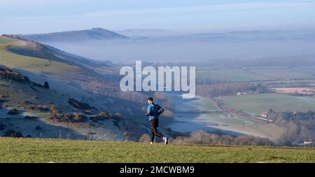 Brighton UK 22. Januar 2023 - Ein Läufer genießt neblige Blicke von Devils Dyke entlang des South Downs Way in der Nähe von Brighton an einem wunderschönen sonnigen, aber kalten Morgen : Credit Simon Dack / Alamy Live News Stockfoto