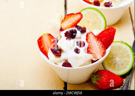 Obst- und Joghurtsalat gesundes Frühstück auf einem weißen Holztisch Stockfoto