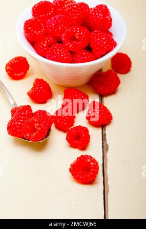 Ein paar frische Himbeeren auf einer Schüssel und ein rustikaler Tisch aus weißem Holz Stockfoto