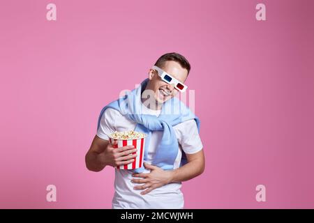 Junger kaukasischer Mann in 3D Gläsern, der Popcorn isst Stockfoto